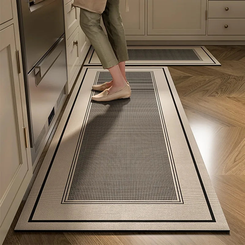 Tapis décoratif gris et noir au sol dans une cuisine avec des armoires blanches.