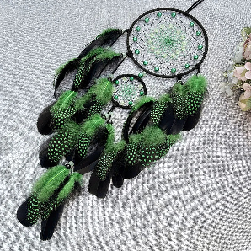 Un joli capteur de rêves aux tons verts et noirs, orné de plumes et de perles, créant une atmosphère mystique et apaisante.