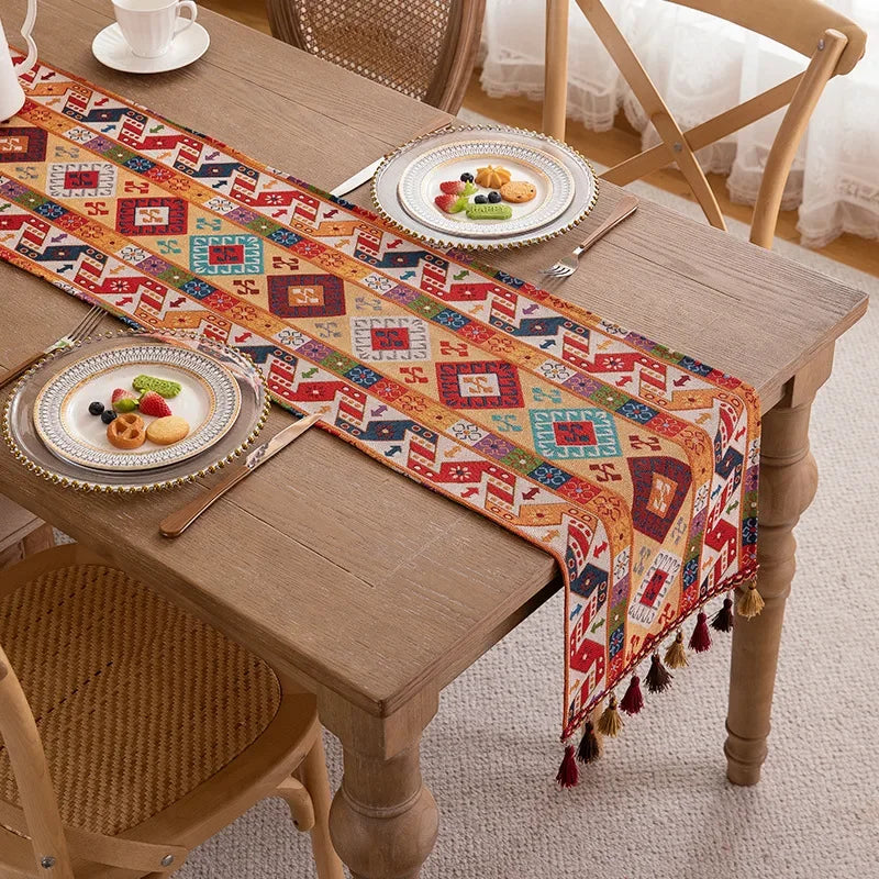 Une table en bois rustique avec des assiettes de fruits et un chemin de table coloré aux motifs ethniques.
