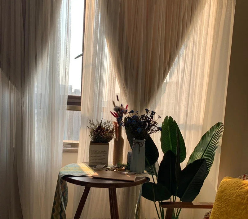 Rideaux légers laissant entrer la lumière naturelle dans un salon élégant, décoré avec des plantes vertes et des bouquets de fleurs séchées sur une table en bois, créant une ambiance chaleureuse et apaisante. Parfaits pour un intérieur moderne et chaleureux.
