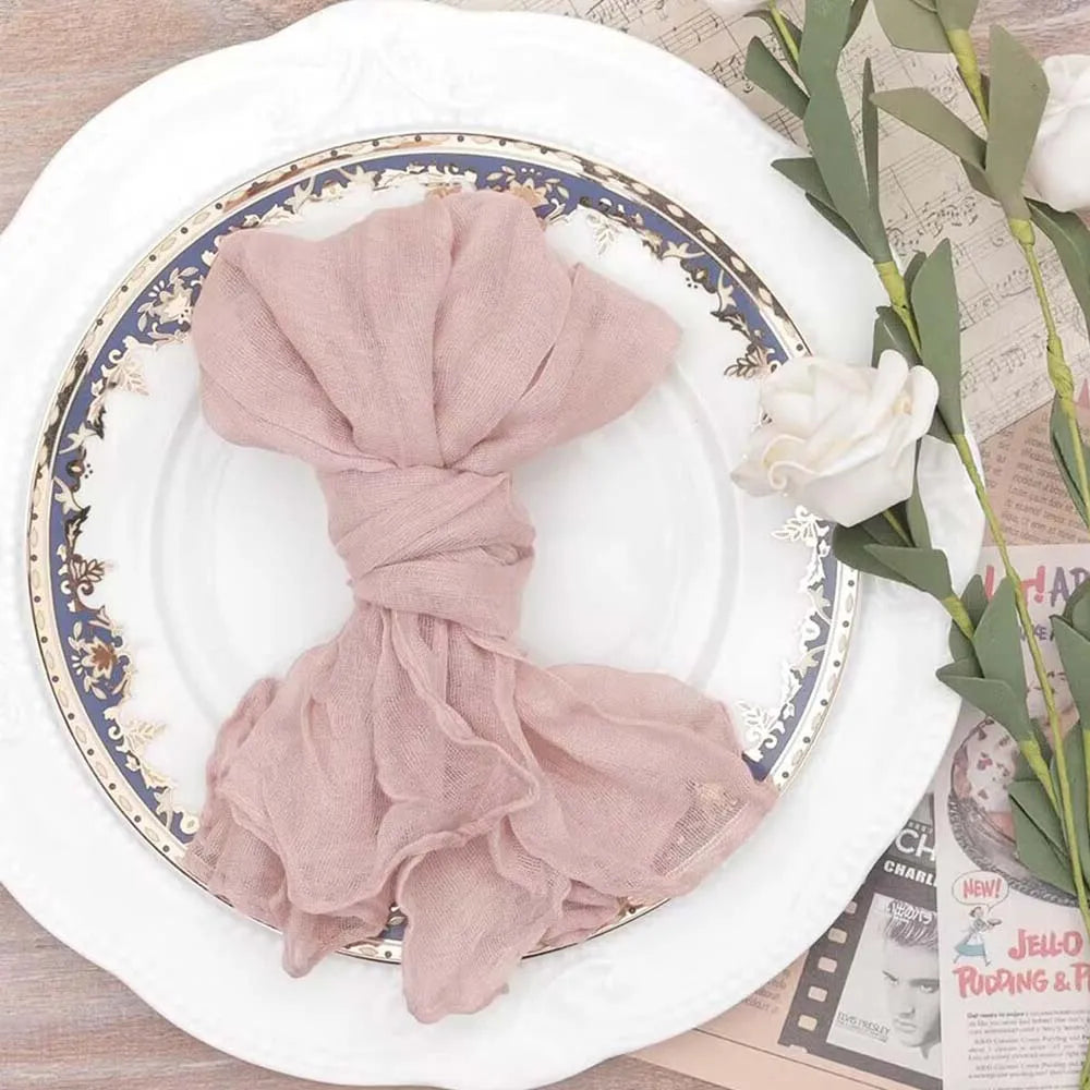 Serviette de table enroulée de manière artistique sur une assiette de porcelaine ornée de motifs floraux, accompagnée de quelques éléments décoratifs.