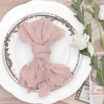 Serviette de table enroulée de manière artistique sur une assiette de porcelaine ornée de motifs floraux, accompagnée de quelques éléments décoratifs.