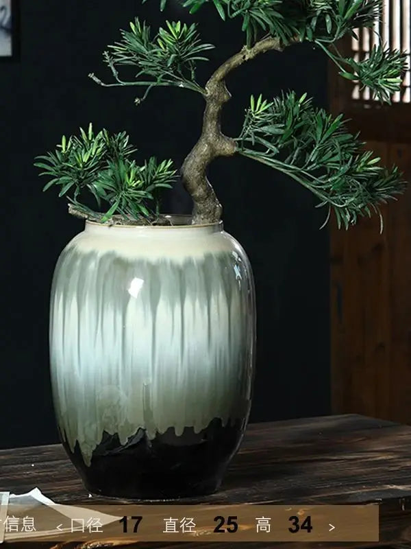 Vase en céramique de couleur vert pâle et noir avec une plante en pot bonsaï sur une étagère en bois.
