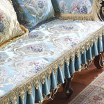 Magnifique nappe et coussins au motif floral élégant et raffiné, rehaussé par une splendide finition de dentelle dorée, créant une ambiance luxueuse et chaleureuse dans cette pièce d'intérieur.