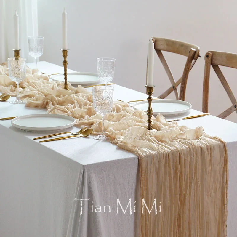 Une table de salle à manger élégante et raffinée, avec des verres cristallins, des bougies en laiton et une nappe en tissu froissé.