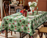 Une nappe de Noël avec des motifs de sapins et de Pères Noël est disposée sur une table de salle à manger.
