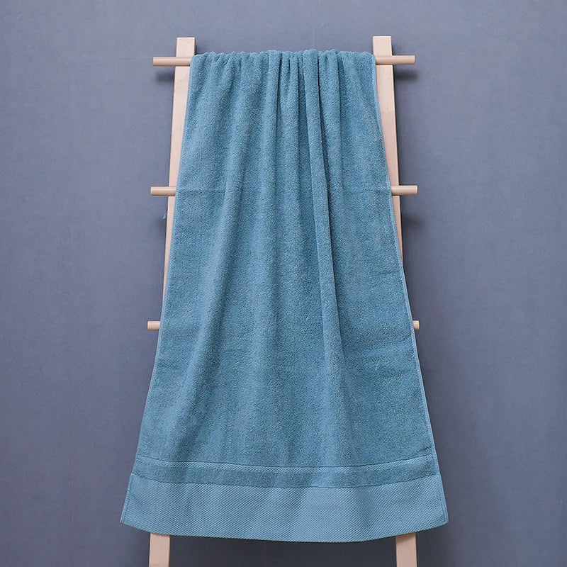 Une serviette de bain bleue pâle suspendue sur un porte-serviette en bois, offrant un look élégant et relaxant dans une salle de bain.