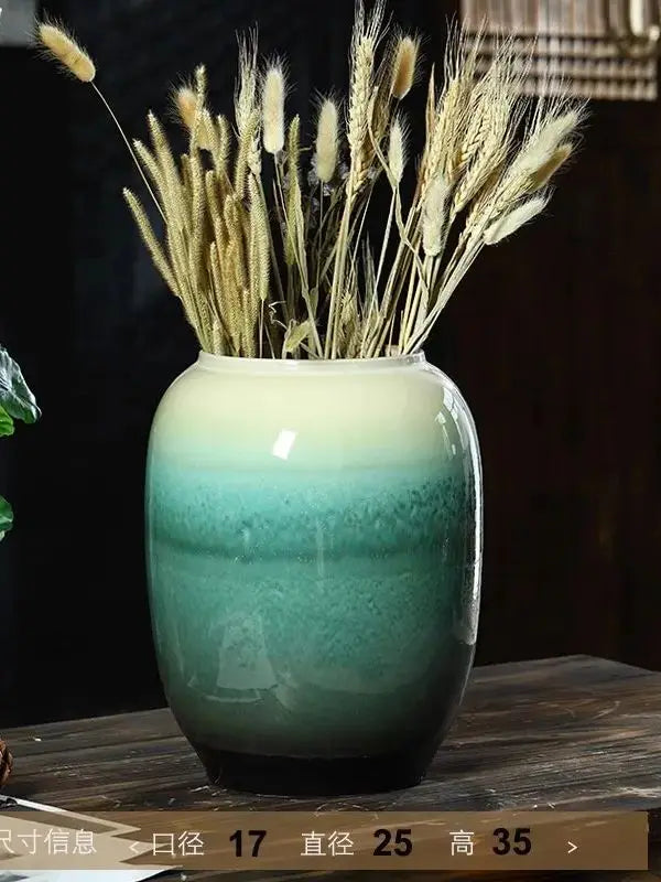 Un vase de céramique vert émaillé rempli de tiges de blé doré, créant une composition naturelle et élégante.