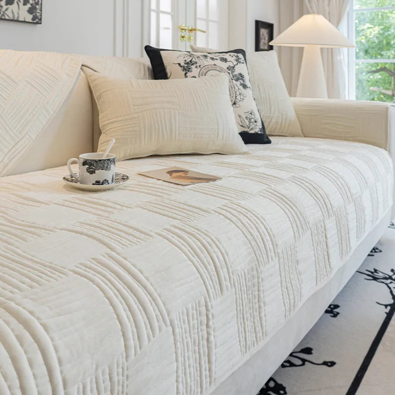 Un magnifique canapé blanc et douillet, avec des coussins coordonnés, offre un confort et une atmosphère chaleureuse dans cette pièce lumineuse.