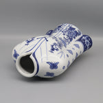 Vase décoratif blanc et bleu avec des motifs floraux et des papillons.
