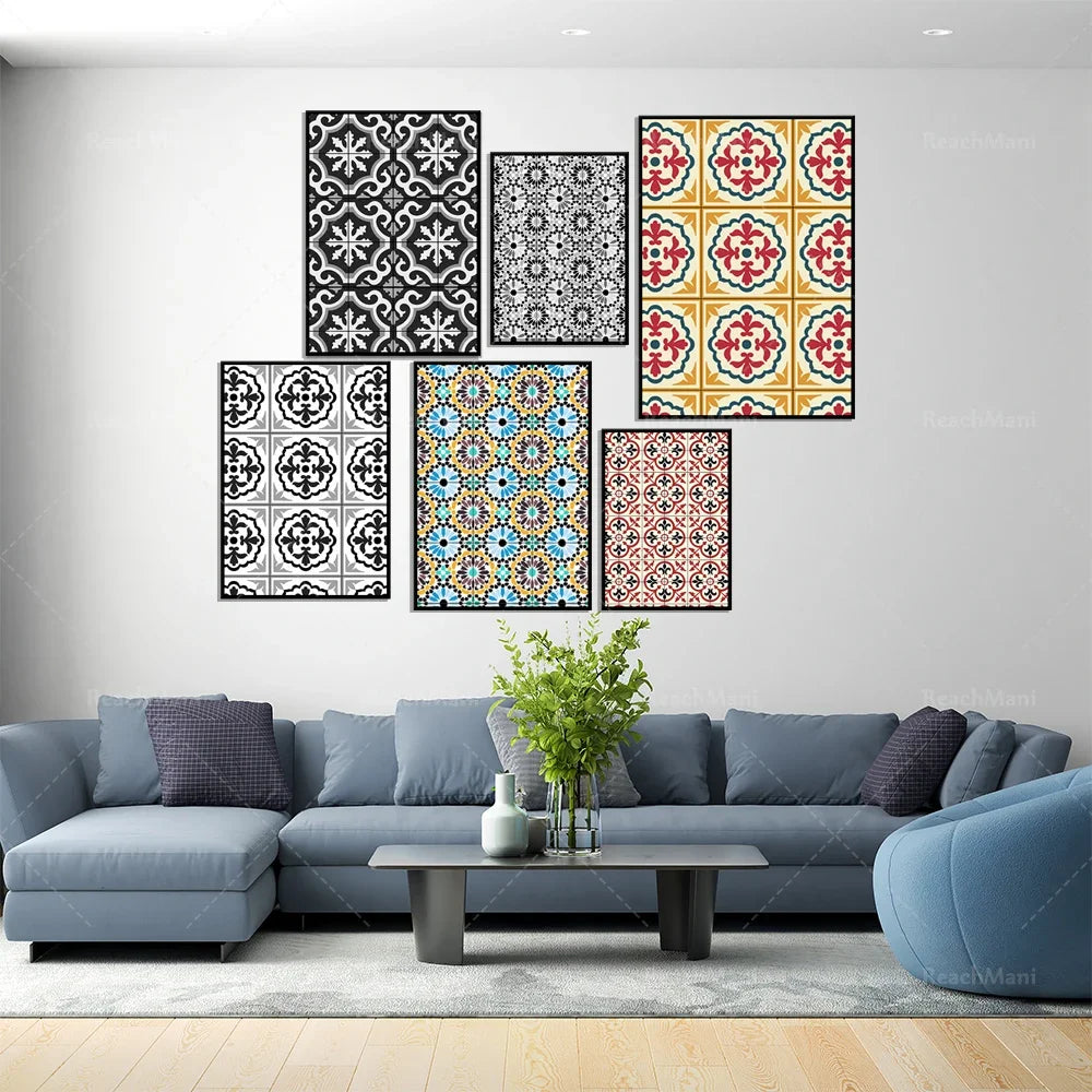Ensemble de cadres décoratifs muraux avec des motifs géométriques variés dans les tons de noir, blanc, rouge et bleu, disposés sur un mur blanc au-dessus d'un canapé gris foncé dans un salon lumineux.