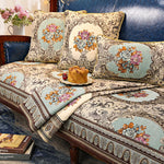 Des coussins décoratifs élégants, aux motifs floraux colorés et ornés de motifs décoratifs sur un canapé de style vintage, créant une atmosphère chaleureuse et accueillante dans la pièce.