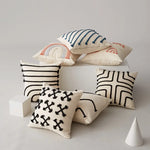 Une collection de coussins décoratifs avec des motifs géométriques et colorés sur un fond clair.
