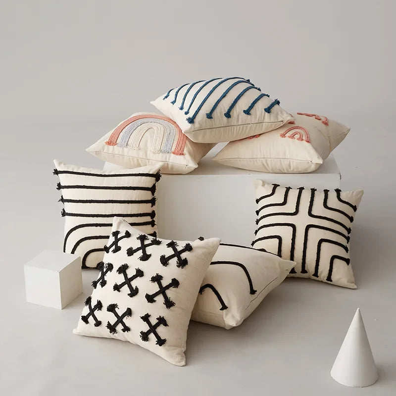 Une collection de coussins décoratifs avec des motifs géométriques et colorés sur un fond clair.