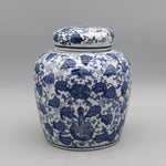 Pot de porcelaine décoré de motifs floraux bleus et blancs sur un fond gris neutre.