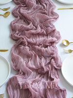 Un somptueux chemin de table rose pâle à froissures élégantes, accompagné d'accessoires dorés, créant une atmosphère sophistiquée et raffinée.