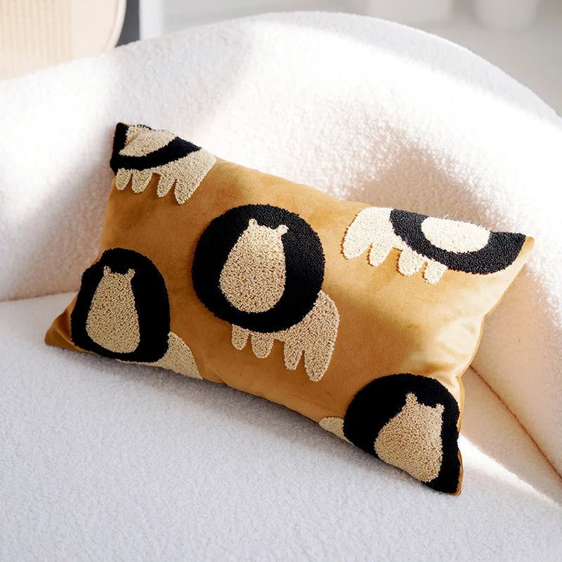 Oreiller décoratif beige avec motifs de pingouins noirs et blancs sur une couverture blanche.