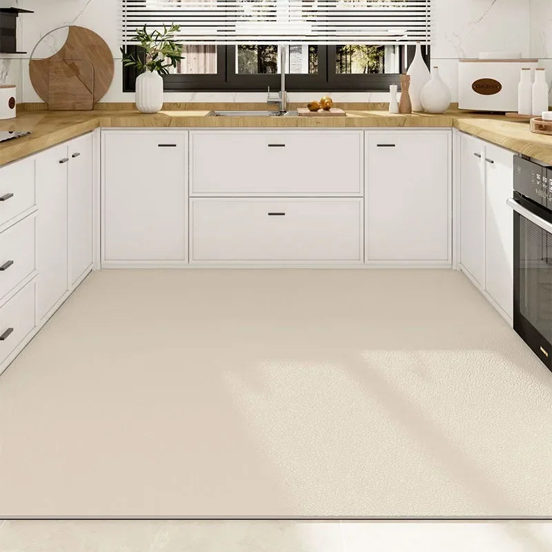 Cette cuisine moderne et épurée présente des meubles blancs et un plan de travail en bois clair, offrant un espace de rangement et de préparation fonctionnel.
