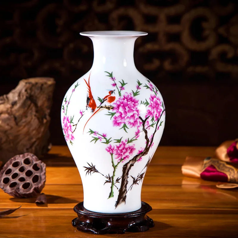 Un vase en porcelaine blanche, décoré de fleurs de cerisier roses épanouies et d'oiseaux colorés, posé sur une surface en bois.