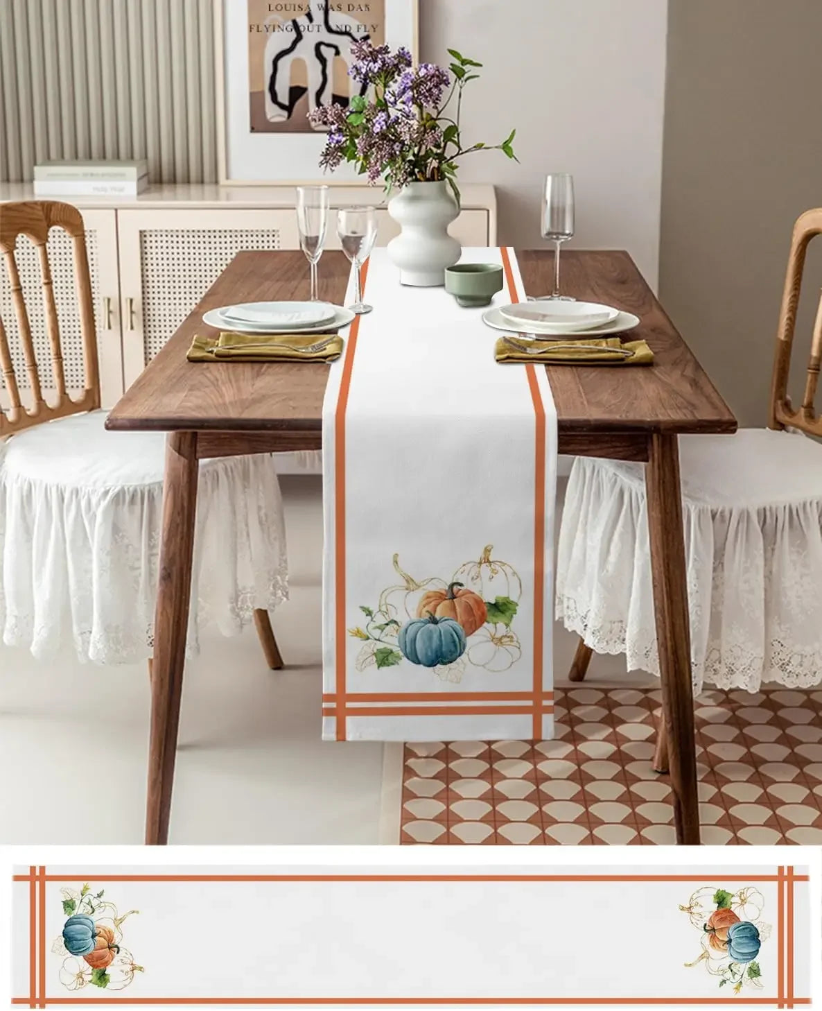 Une table à dîner élégante avec un chemin de table décoré de citrouilles peintes, des verres à vin et une composition florale.