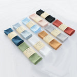 Une collection de carrés de tissu de diverses couleurs, y compris le bleu, le rose, le vert et le doré, emballés individuellement et portant l'étiquette "Vantting".