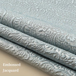L'image montre un motif embossé élégant sur un tissu jacquard gris, créant un effet textile luxueux et délicat.