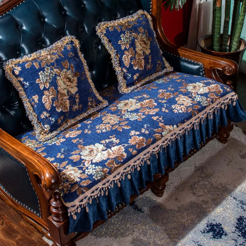 Luxueuse banquette tapissée de motifs floraux bleu foncé et dorés, rehaussée de volants et de franges, offrant un style élégant et vintage dans un cadre d'ameublement classique.