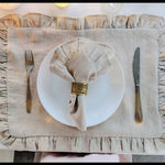 Une élégante décoration de table avec des serviettes ornées de volants et un accesoire doré pour un raffinement chic.