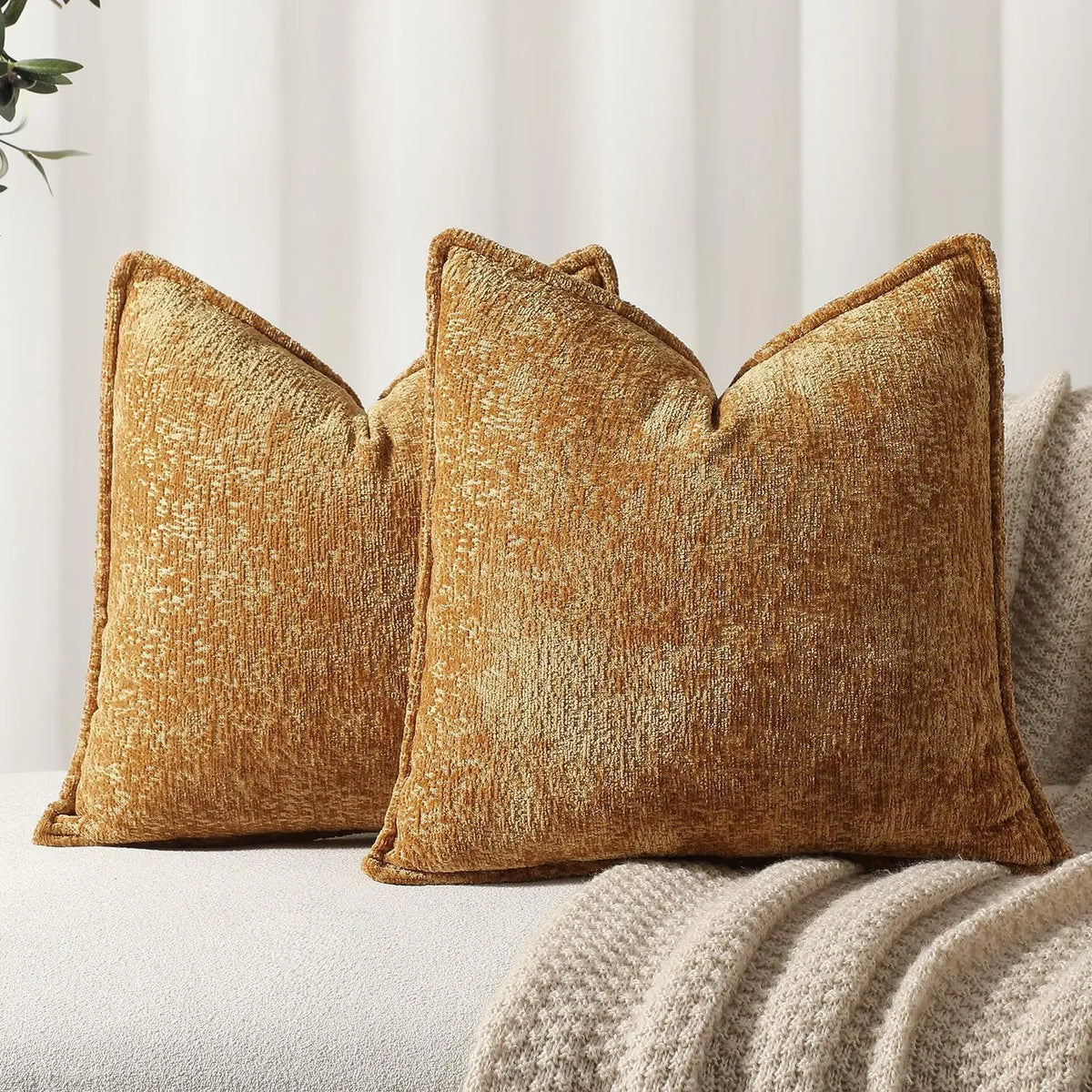 Trois coussins décoratifs en velours doré posés sur un canapé, créant une ambiance chaleureuse et accueillante dans la pièce.