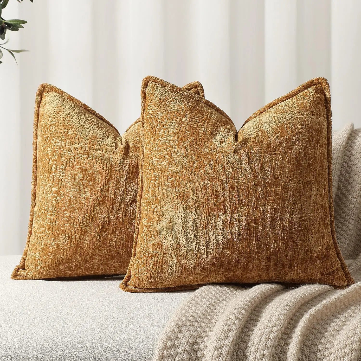 Trois coussins décoratifs en velours doré posés sur un canapé, créant une ambiance chaleureuse et accueillante dans la pièce.