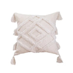 Coussin décoratif en tissu beige délavé avec des motifs géométriques et des franges ornementales, créant une atmosphère chaleureuse et cocooning dans un intérieur contemporain.