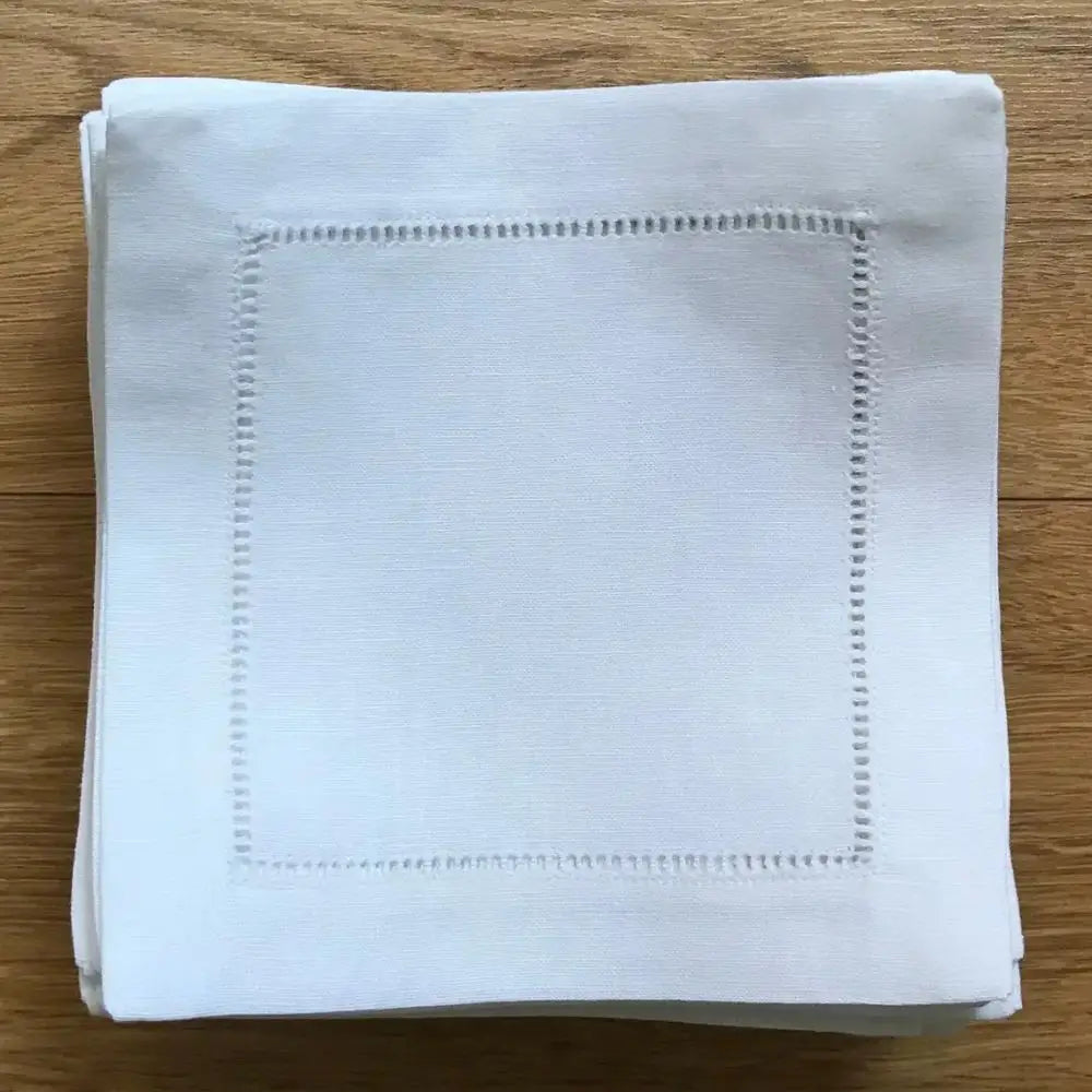 Serviette blanche avec bordure en pointillés sur fond en bois.