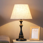 Lampe de chevet en lin blanche sur table de nuit