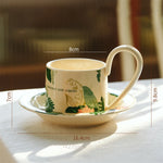 Tasse en porcelaine avec fleurs et motifs de feuilles, accompagnée d'une soucoupe, créant un ensemble élégant pour la dégustation d'une boisson chaude.