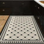Carrelage de sol vintage à motif géométrique noir et blanc dans une cuisine avec des meubles de cuisine noirs.
