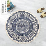 Un tapis rond aux motifs ethniques et décoratifs, avec des ornements et des arabesques complexes en bleu foncé sur un fond blanc.
