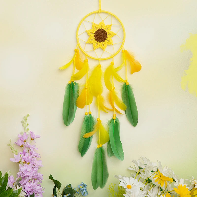 Magnifique attrape-rêves en forme de fleur de tournesol avec des plumes vertes et jaunes, suspendu sur un fond clair orné de fleurs fraîches.