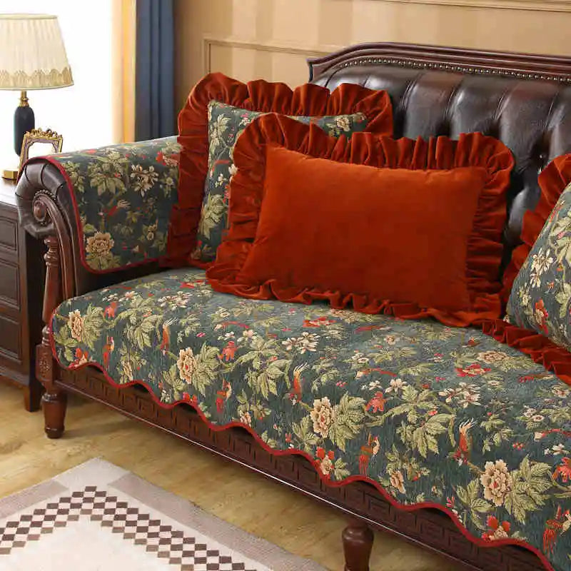 Un canapé en cuir brun orné de coussins rouges décoratifs et d'un jeté de lit fleuri, créant une ambiance chaleureuse et élégante dans cette pièce meublée avec goût.