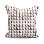 Coussin décoratif avec des silhouettes de chats imprimées dans des tons neutres, créant un motif répétitif et graphique.