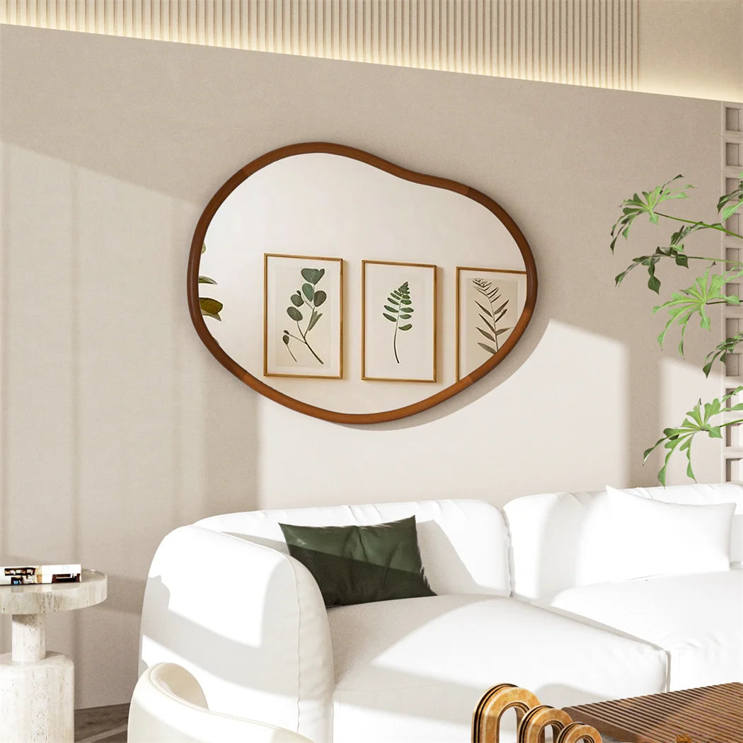 Salon élégant avec miroir mural ovale en bois, cadres décoratifs de feuillage et canapé blanc confortable.