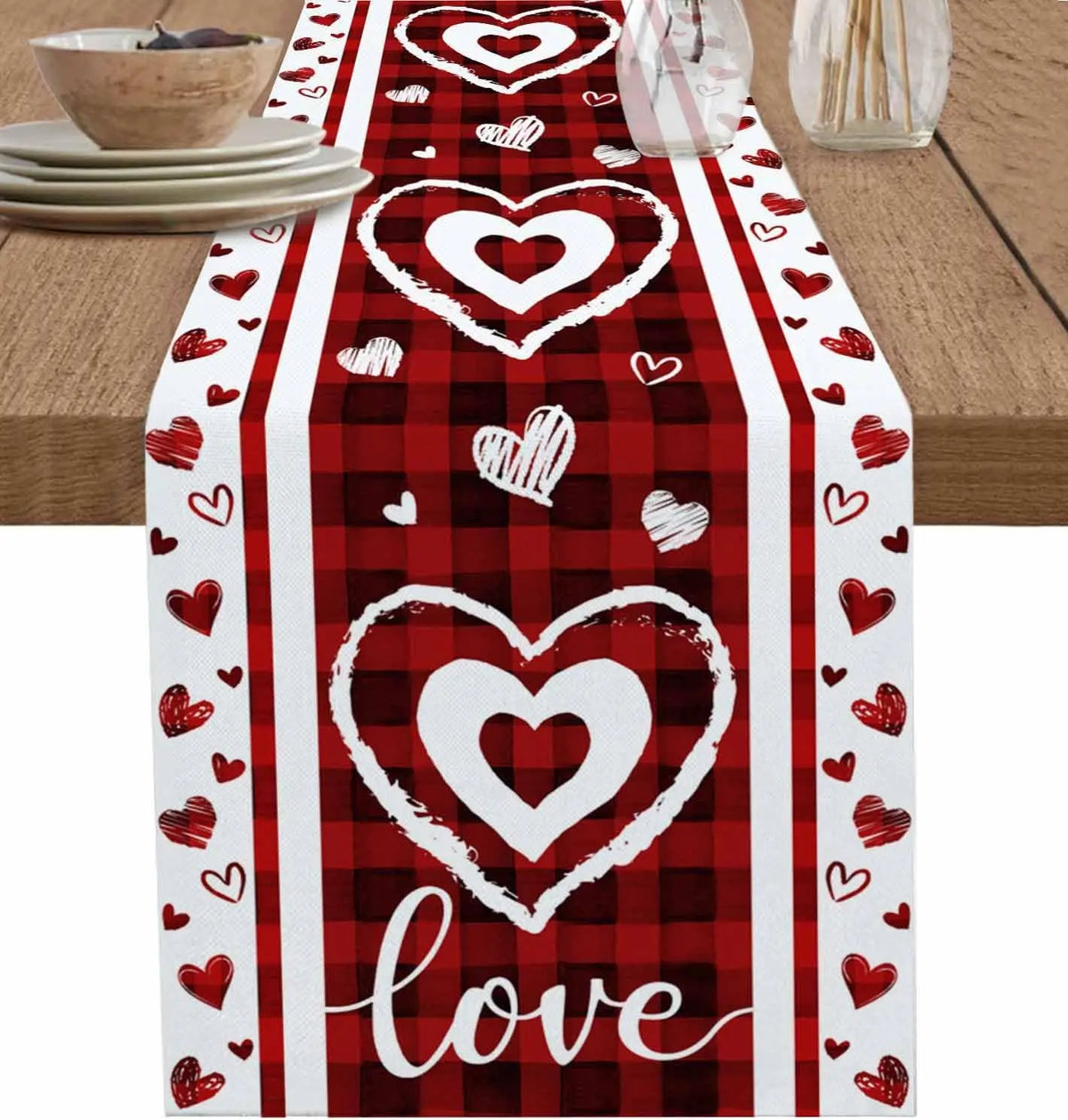 Chemin de table rouge à carreaux avec des coeurs blancs et le mot "Amour" au centre, créant une ambiance romantique et festive.