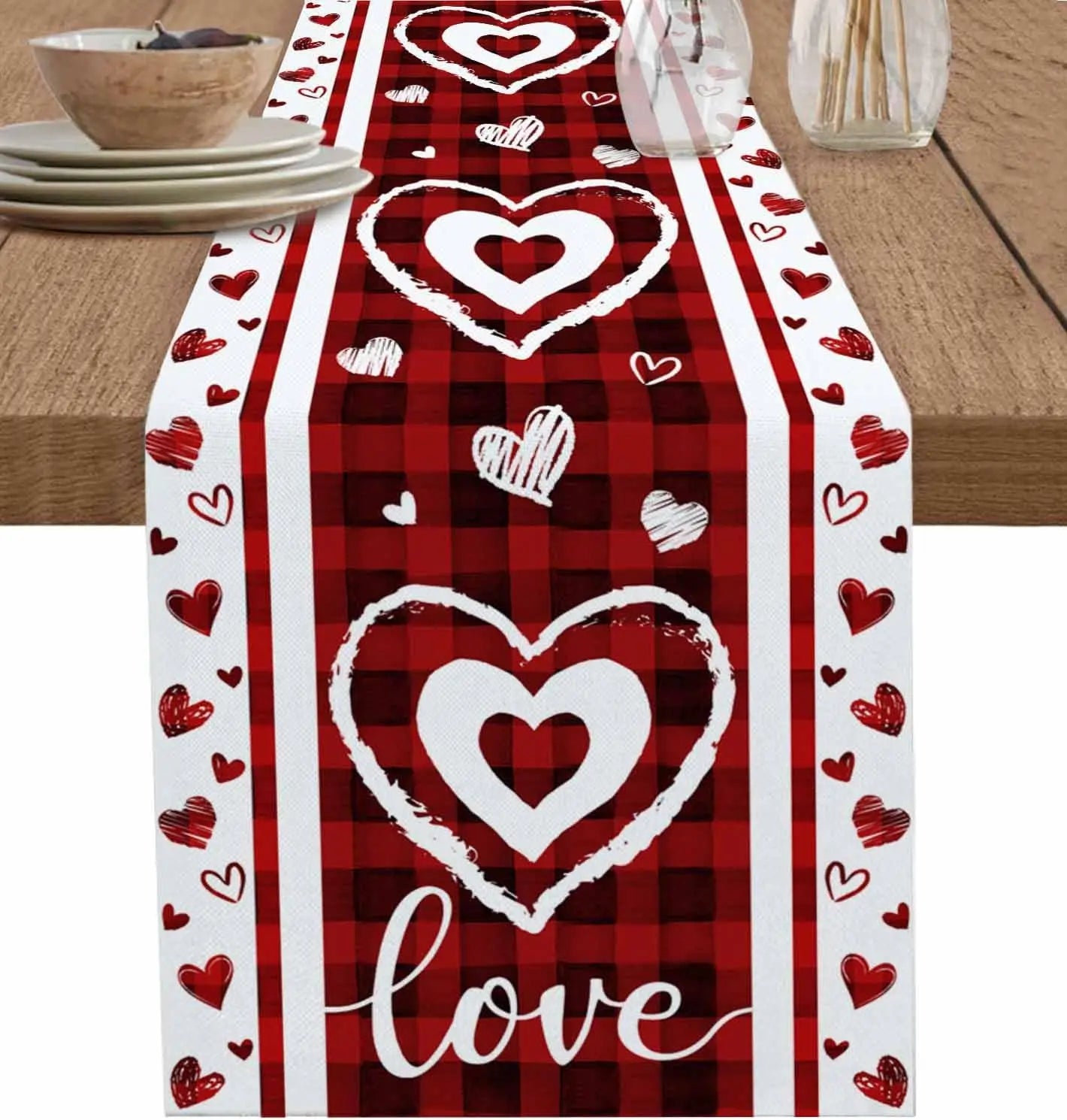 Chemin de table rouge à carreaux avec des coeurs blancs et le mot "Amour" au centre, créant une ambiance romantique et festive.