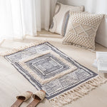 Tapis et coussins décoratifs avec motifs géométriques ethniques dans un intérieur lumineux et minimaliste.