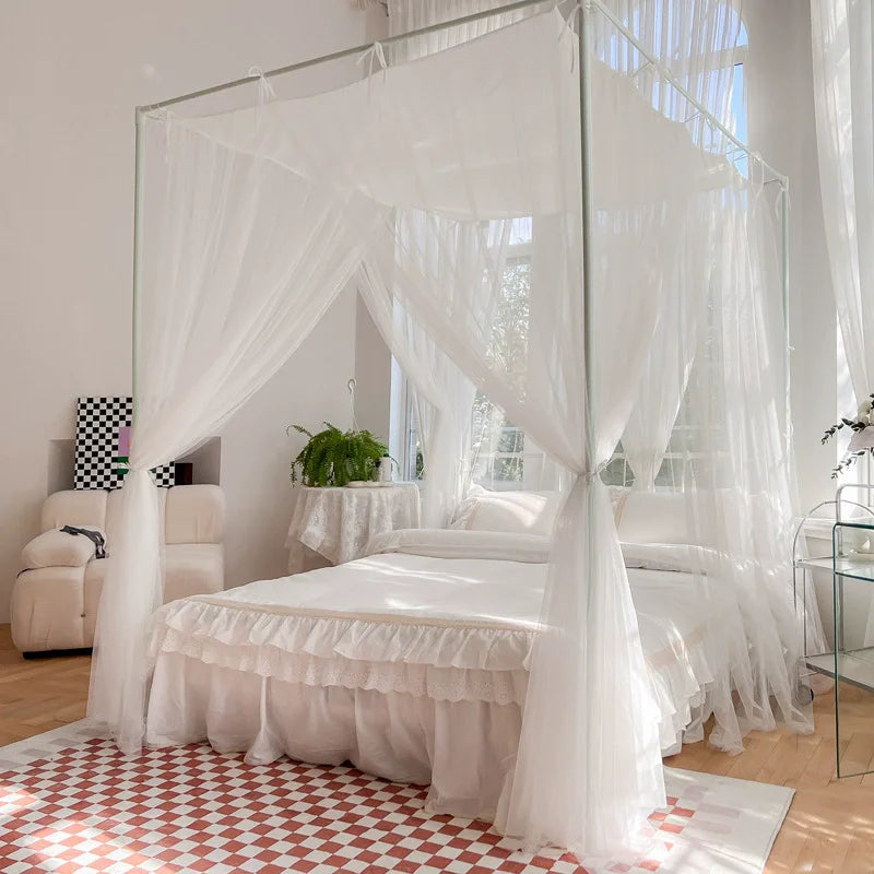Chambre blanche et lumineuse avec un lit à baldaquin et des rideaux transparents, posée sur un carrelage à motifs géométriques rouges et blancs.