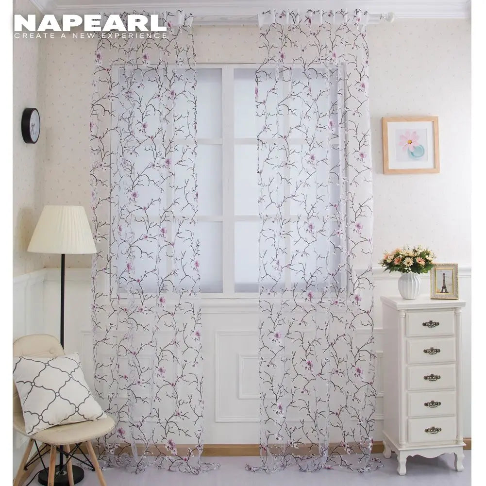 Détail des motifs floraux violets sur le rideau en tulle
