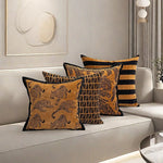 Des coussins décoratifs de style tribal avec des motifs géométriques et animaux sur un canapé blanc, créant une ambiance chaleureuse et élégante dans la pièce.