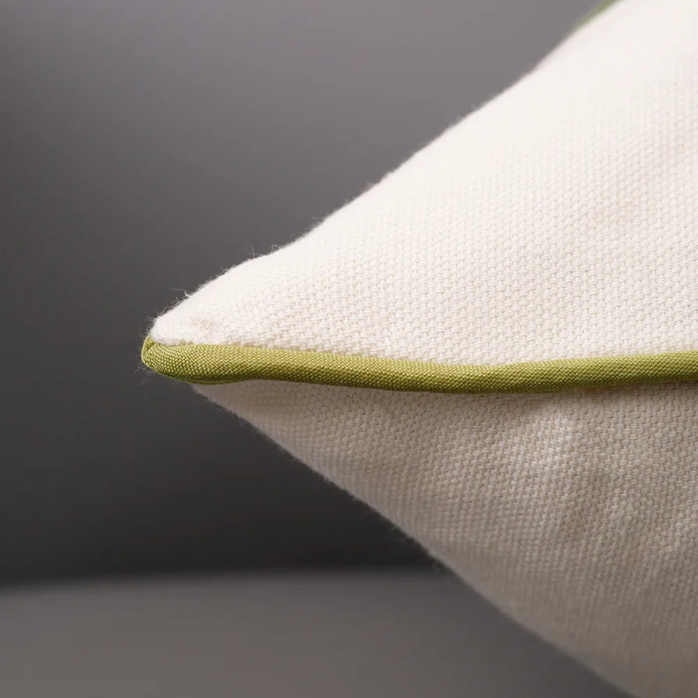 Gros plan d'un coussin blanc et vert avec un bord en satin vert.