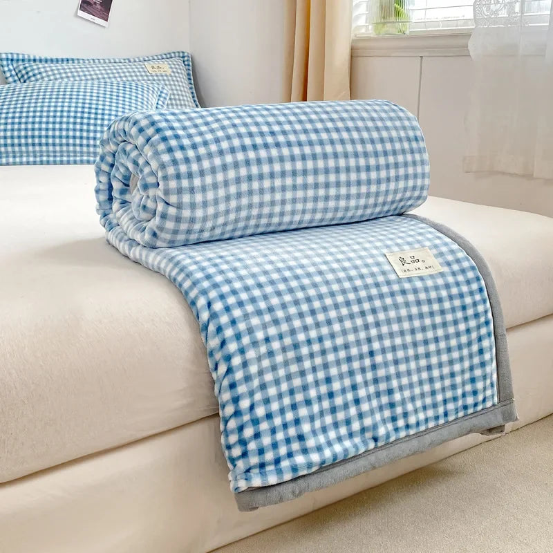 Couverture douillette à motif de petits carreaux bleus et blancs, posée sur un canapé beige.