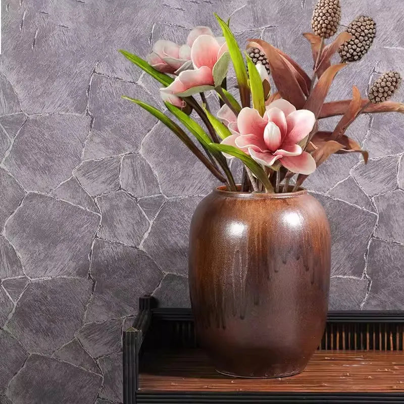 Un bouquet de fleurs roses élégantes dans un vase en bois posé sur une étagère en bois sur un mur de pierre grise.