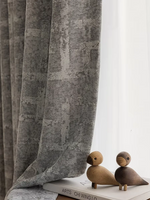 Rideau occultant gris moderne avec motif géométrique subtil, idéal pour ajouter une touche élégante à votre salon ou chambre. Accessoires décoratifs boisés à côté pour une ambiance chaleureuse.